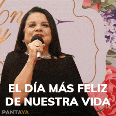 a woman singing into a microphone with the words el dia mas feliz de nuestra vida behind her
