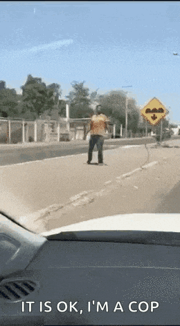 a man is walking down a street with a sign that says it is ok i 'm a cop .