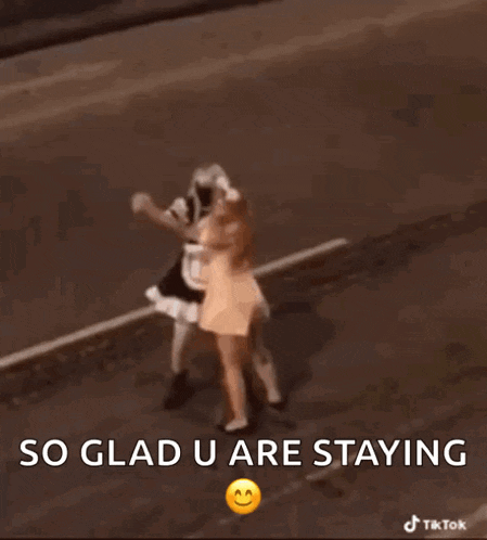 two women dressed as maids are dancing on the side of a road .