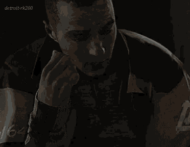 a close up of a man 's face in a dark room with his hand on his face .