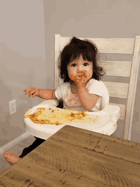 a little girl is sitting in a high chair eating
