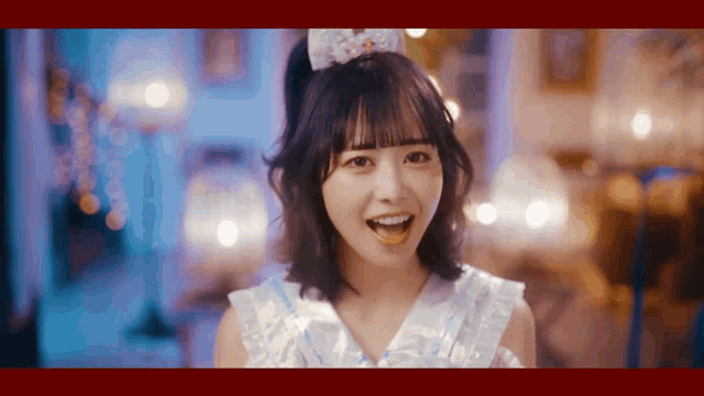 a girl in a white dress with a bow on her head is smiling