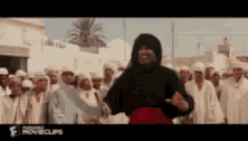 a man wearing a black hooded jacket is standing in front of a crowd of people .