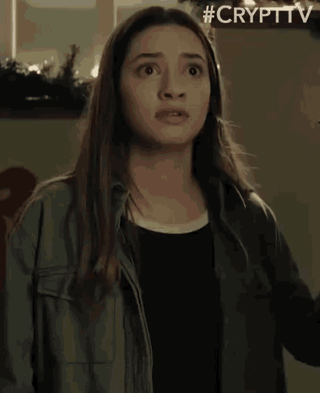a young woman in a green jacket is making a funny face .