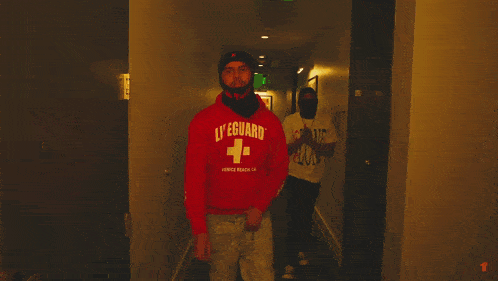 a man wearing a red figured sweatshirt holds his fist up