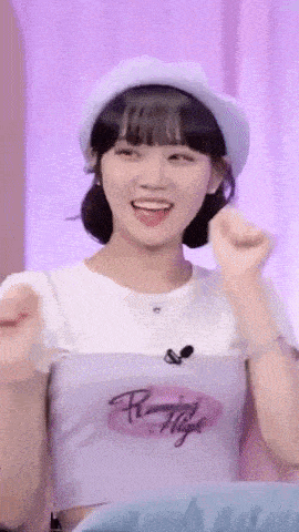 a woman wearing a white hat and a purple shirt is smiling and making a fist .
