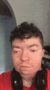 a man wearing headphones and a red shirt looks at the camera .