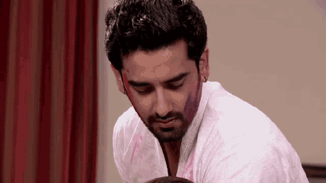 a man with holi paint on his face is looking down