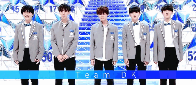 a group of young men in suits and bow ties are standing in front of a wall with the word team dk written on it