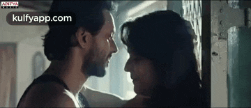 a man and a woman are looking into each other 's eyes in a room .
