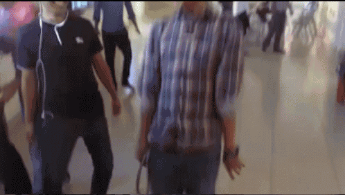 a blurry picture of people walking in a hallway with one wearing a burberry shirt