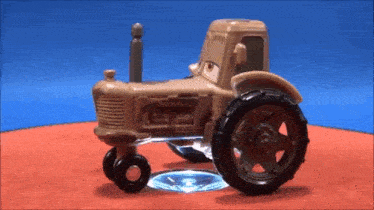 a toy tractor is sitting on top of a red surface
