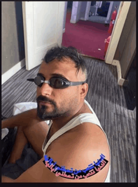 a man with a beard wearing swimming goggles and a white tank top