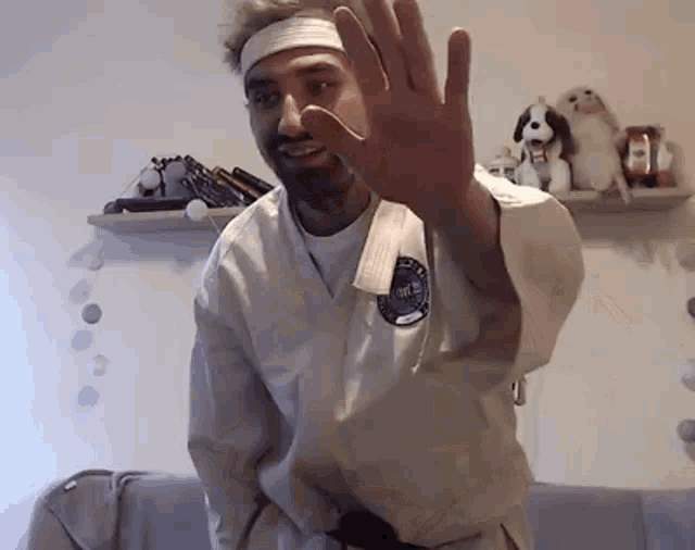 a man in a karate uniform is waving his hand