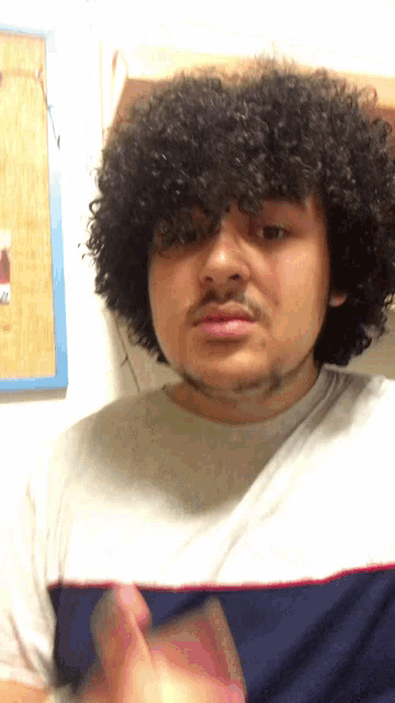 a man with curly hair and a beard is wearing a white shirt