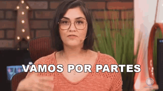 a woman wearing glasses and a pink sweater says vamos por partes in spanish