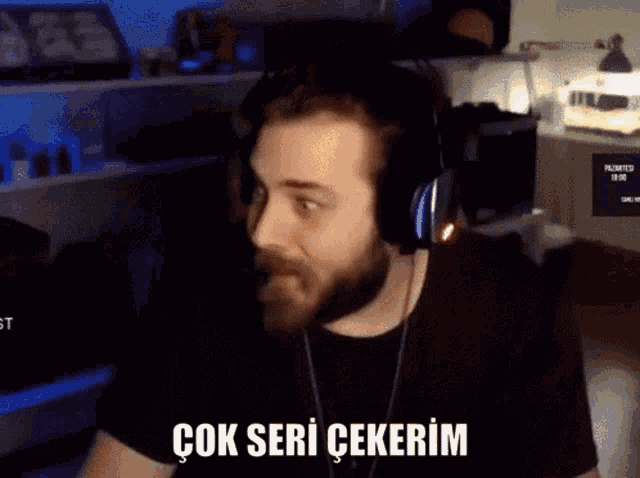 a man with a beard is wearing headphones and says " çok seri cekerin "