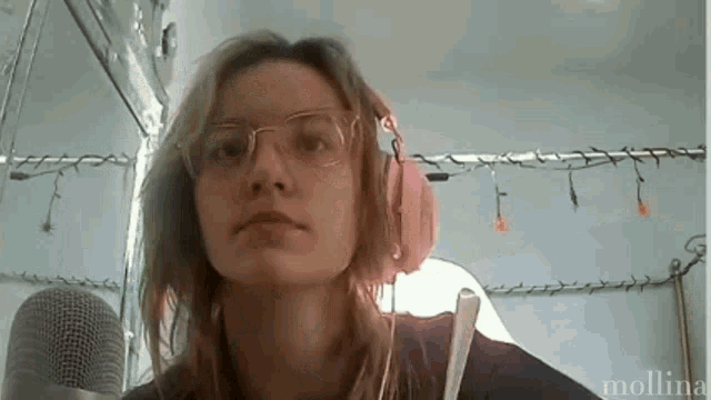 a woman wearing glasses and headphones stands in front of a microphone with the name molina written below her