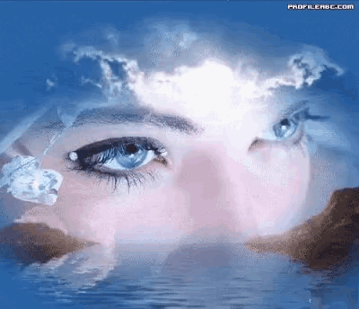 a close up of a woman 's face with blue eyes and mountains in the background .