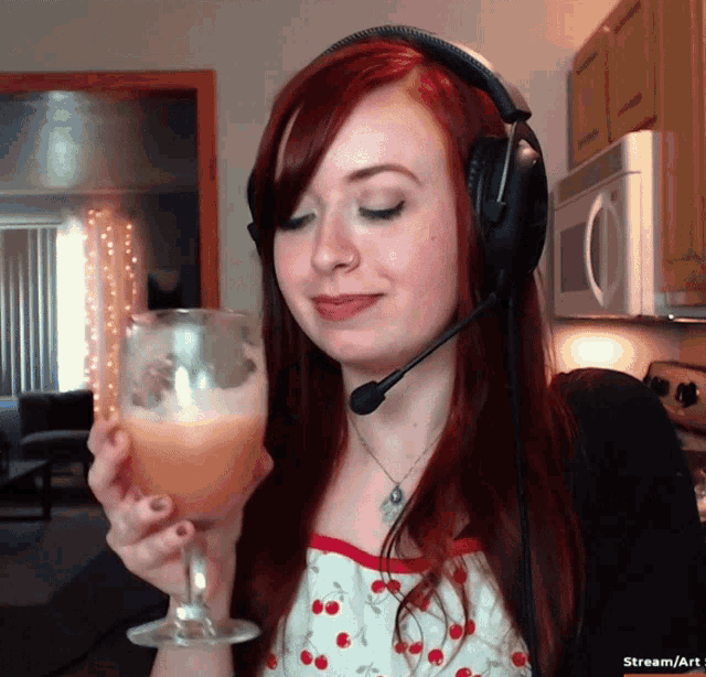 a woman wearing headphones and holding a glass of orange liquid