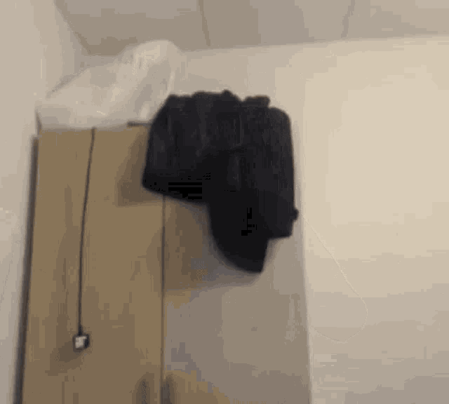a black jacket is hanging on a wooden closet door
