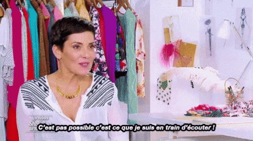 a woman is standing in front of a rack of clothes and says " c'est pas possible " in french