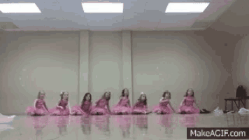 a group of little girls in pink tutus are sitting on the floor in a room .