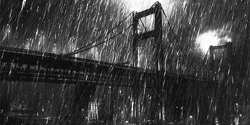 a black and white photo of a bridge in the rain at night