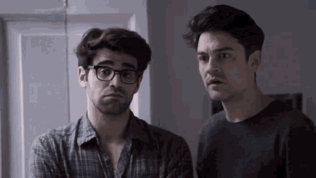 two men are standing next to each other and one of them has glasses on