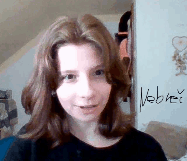 a girl with red hair is smiling in front of a sign that says nebrer