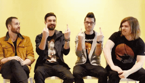four men are sitting in a row with one wearing a shirt that says " allow "