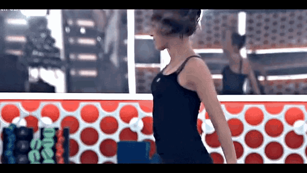 a woman in a black tank top is standing in front of a red and white polka dot wall ..