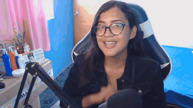 a woman wearing glasses is sitting in a chair with a microphone on it