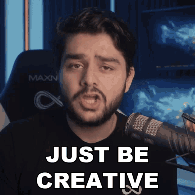 a man with a beard stands in front of a microphone and says " just be creative "
