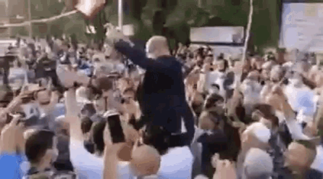 a man is being lifted in the air by a crowd of people at a concert .
