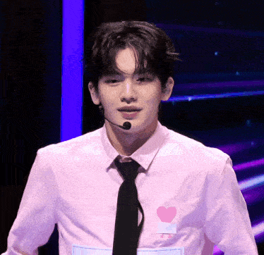 a man wearing a pink shirt and black tie has a heart on his shirt
