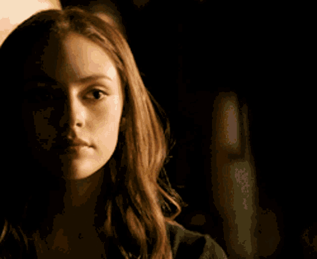 a close up of a woman 's face in a dark room looking to the side .