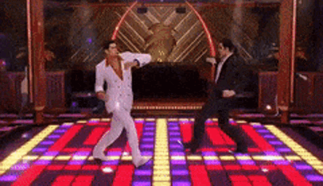 two men in suits are dancing on a colorful dance floor .