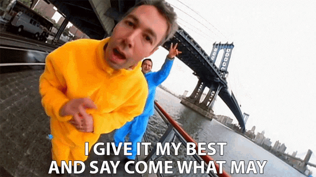 a man in a yellow sweater says i give it my best and say come what may in front of a bridge