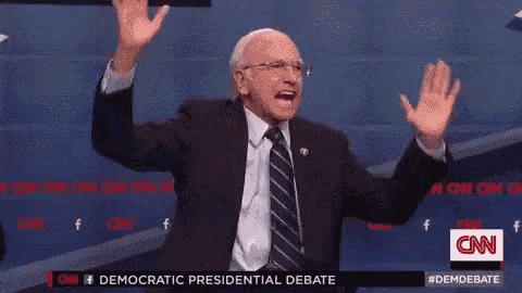 a man in a suit and tie is giving a high five at a cnn debate