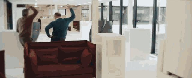 a man stands in front of a red couch in a room