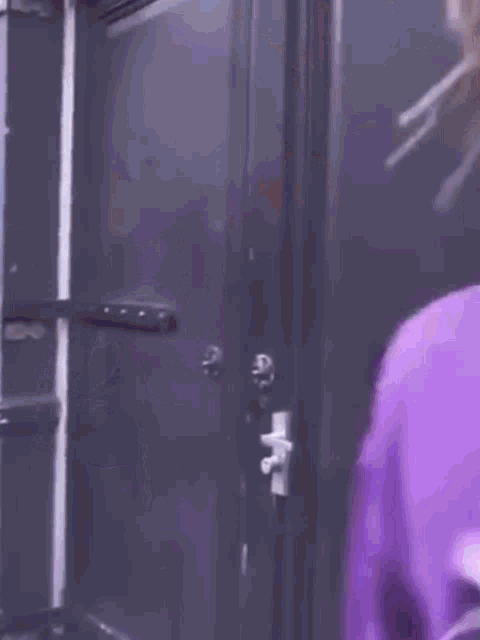 a person wearing a purple hoodie and headphones is standing in front of a door .