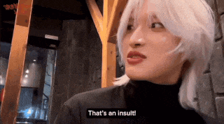 a woman with white hair is making a funny face and saying that 's an insult .