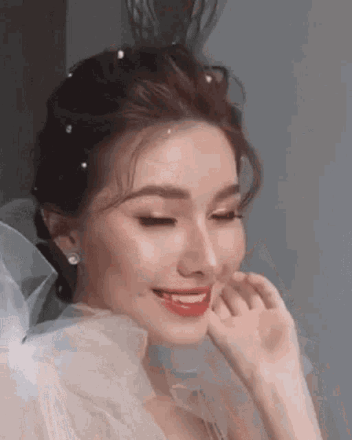 a close up of a woman wearing a white dress and pearls in her hair .