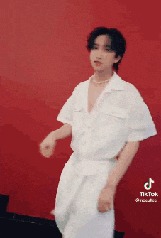 a man in a white shirt is dancing in front of a red background .
