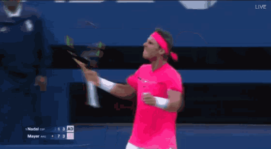 a man in a pink shirt and headband is holding a tennis racket .