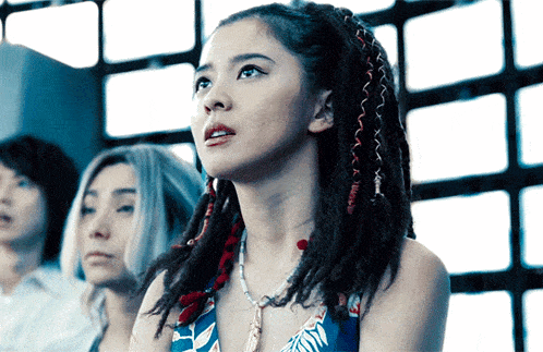 a woman with dreadlocks is wearing a necklace and looking up