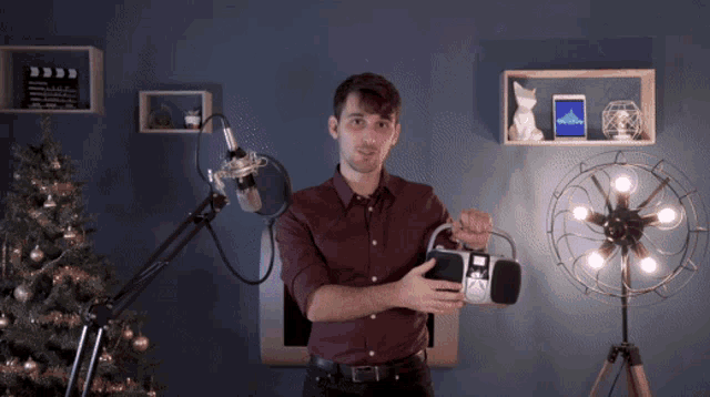 a man in a red shirt is holding a radio in front of a microphone