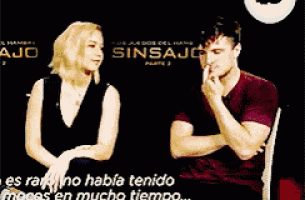 a man and a woman are sitting next to each other in front of a sign that says sin sajo