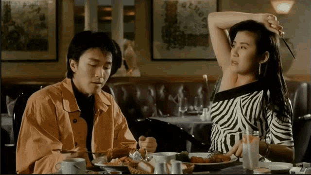 a man and a woman are sitting at a table in a restaurant eating food